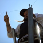 An Ultra Orthodox Jewish man stands on a  ladder and hangs "Eruv" (Eiruv or Erub) wire, near the Gilo neighborhood in south Jerusalem, on Friday, Aug 14, 2009. A community Eruv refers to the legal aggregation or "mixture" under Jewish religious property law of separate parcels of property meeting certain requirements into a single parcel held in common by all the holders of the original parcels, which enables Jews who observe the traditional rules concerning Shabbat to carry children and belongings anywhere within the jointly held property without transgressing the prohibition against carrying a burden across a property line on the Jewish sabbath. Photo by Nati Shohat / FLASH90. *** Local Caption *** òéøåá
çåè
òîåã
çøãéí
çøãé
éøåùìéí